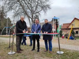 Szász József alpolgármester, Vass Pál önkormányzati képviselő és Kovács Péter polgármester átvágják a szalagot a felújított Emma utcai játszótérnél.